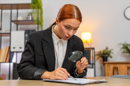 Surprised woman examining financial documents with a magnifying glass, representing the discovery of hidden car finance commissions and unexpected charges.